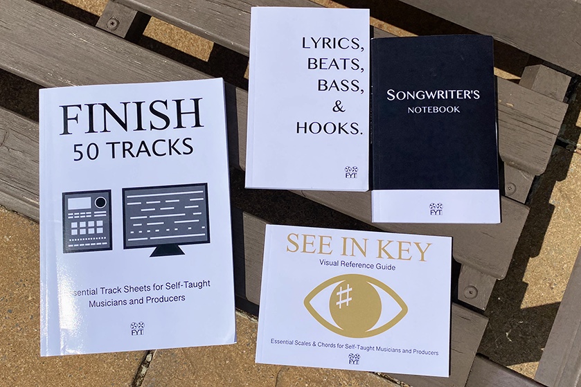 A collection of Finish Your Tracks books on a bench in the sunshine for our etsy shop